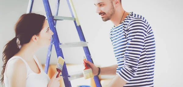 Retrato feliz sonriente joven pareja pintura interior de la pared de la nueva casa —  Fotos de Stock