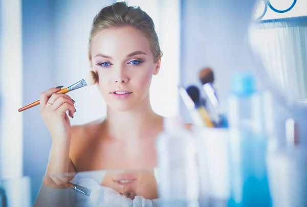 Jonge mooie vrouw maken make-up in de buurt van spiegel, zitten aan de balie — Stockfoto