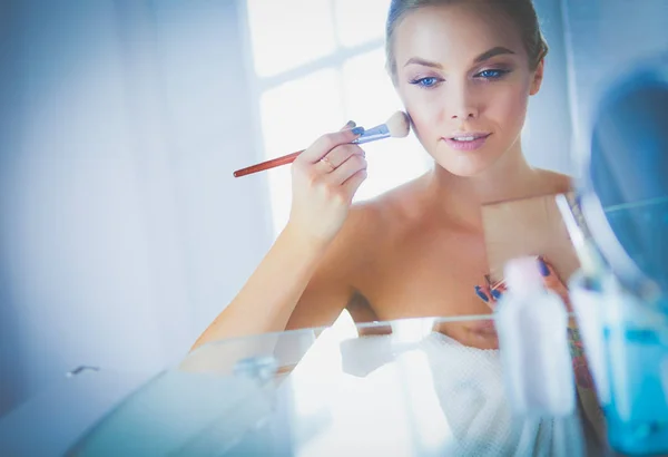 Young beautiful woman making make-up near mirror,sitting at the desk — Stock Photo, Image