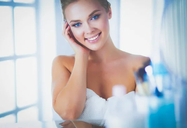 Bella giovane donna si sta toccando il viso e sorridendo guardando lo specchio — Foto Stock