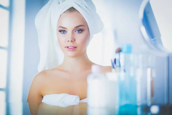 Beautiful young woman is touching her face and smiling while looking at the mirror — Stock Photo, Image