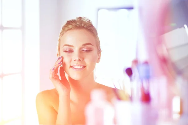 Jonge mooie vrouw maken make-up in de buurt van spiegel, zitten aan de balie — Stockfoto