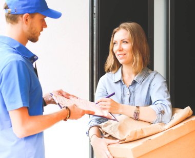 Mavi üniformalı gülümseyen kurye servis konseptine paket kutusu teslim eden teslimatçı. Mavi üniformalı gülümseyen teslimatçı.