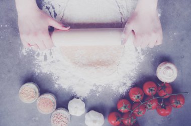 Güzel bir kadın mutfakta pasta pişiriyor. Masanın yanında duruyor..