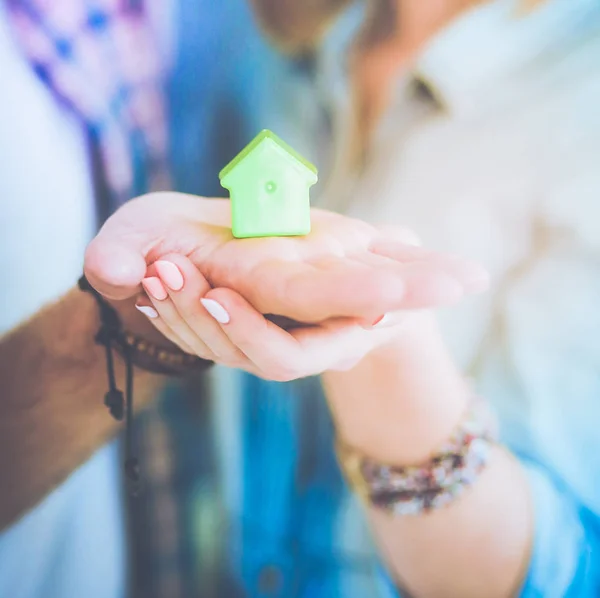 Modelo de casa en la mano de una pareja, de pie en un nuevo hogar. Casa modelo . —  Fotos de Stock