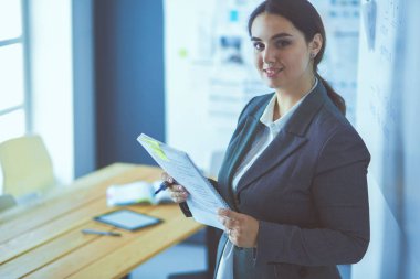 Ayakta ve ofiste bir kitap tutan genç gülümseyen kadın