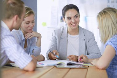 Masada kitaplarla çalışan gençler. Güzel kadınlar ve erkekler birlikte çalışıyor.