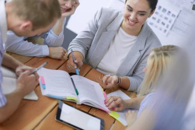 Masada kitaplarla çalışan gençler. Güzel kadınlar ve erkekler birlikte çalışıyor.