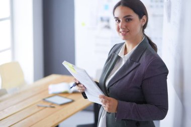 Ayakta ve ofiste bir kitap tutan genç gülümseyen kadın