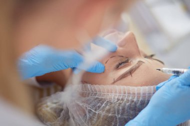 Kaşlar için kalıcı makyaj. Güzellik salonunda kalın kaşlı güzel bir kadın..