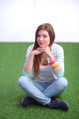 Yeşil çimlerde oturan genç bir kadın. Portreit genç bayan