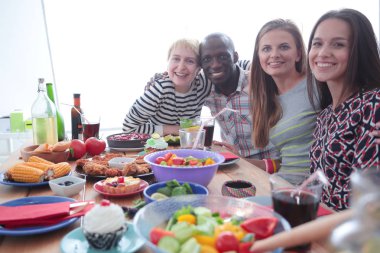 Ahşap masada otururken birlikte yemek yiyen bir grup insanın üst düzey görüntüsü. Masada yemek var. İnsanlar fast food yiyor..