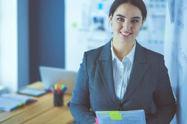 Young smiling woman standing and holding a book in office — Stock Photo, Image