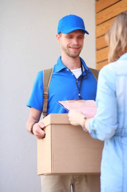 Mavi üniformalı gülümseyen kurye servis konseptine paket kutusu teslim eden teslimatçı. Mavi üniformalı gülümseyen teslimatçı.