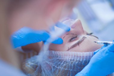 Kaşlar için kalıcı makyaj. Güzellik salonunda kalın kaşlı güzel bir kadın..