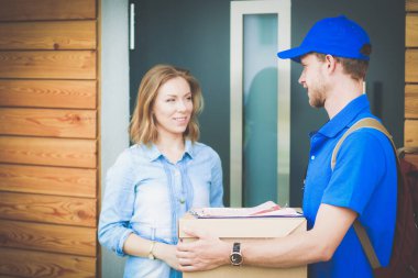 Mavi üniformalı gülümseyen kurye servis konseptine paket kutusu teslim eden teslimatçı. Mavi üniformalı gülümseyen teslimatçı.