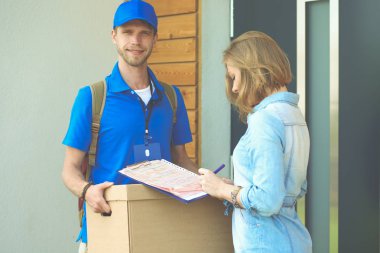 Mavi üniformalı gülümseyen kurye servis konseptine paket kutusu teslim eden teslimatçı. Mavi üniformalı gülümseyen teslimatçı.