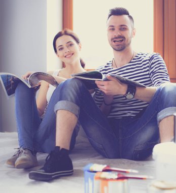 Yeni evin içini boyayan mutlu, gülümseyen genç bir çift portresi. Genç çift