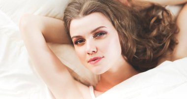 Güzel bir kadın yatağında uzanıyor..
