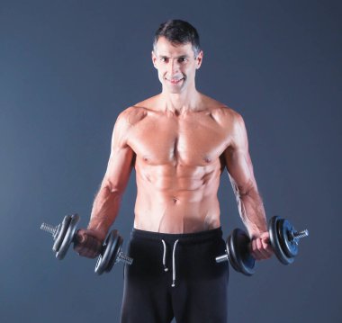 Yakışıklı kaslı adam dumbell ile çalışma dışarı. Kişisel fitness eğitmeni. Kişisel eğitim.