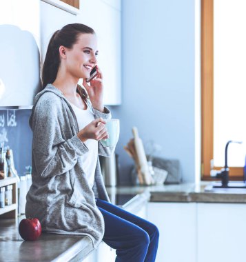 modern mutfakta otururken cep telefonu kullanan kadın.