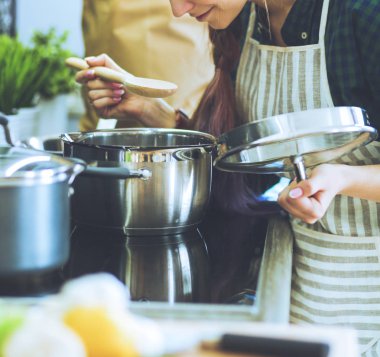 Mutfakta sobanın yanında duran genç bir kadın. .
