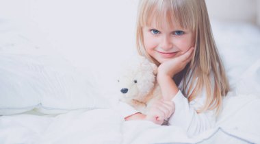 Evde yatakta yatıyordu bir oyuncak ayı ile küçük kız