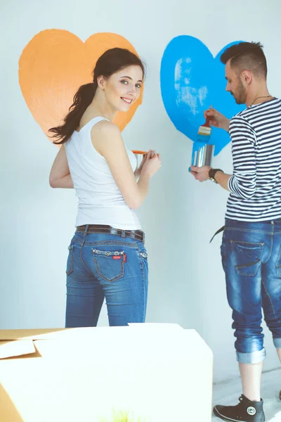 Retrato de feliz casal sorrindo jovem pintura parede interior da nova casa. jovem casal — Fotografia de Stock