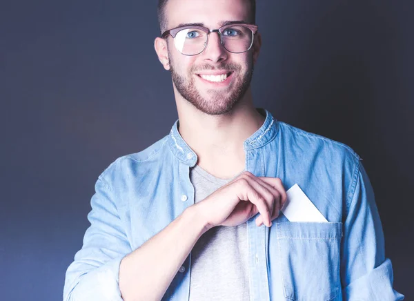 Joven sosteniendo una tarjeta de crédito de pie sobre fondo gris. Joven empresario. — Foto de Stock