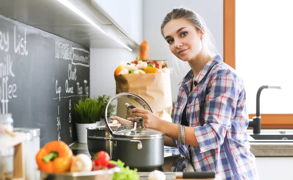 Mutfakta sobanın yanında duran genç bir kadın. .