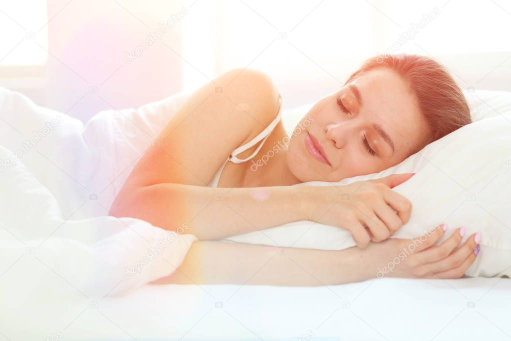 Beautiful girl sleeps in the bedroom, lying on bed.