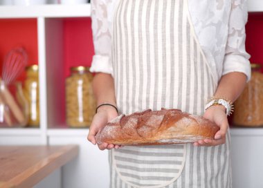 Genç bir kadın mutfağında ekmeği holding ayakta. Genç bir kadın