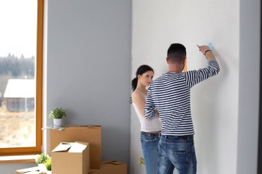 Yeni evin içini boyayan mutlu, genç bir çiftin portresi. Genç çift