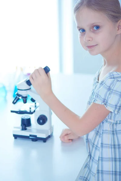 Colegiala mirando a través del microscopio en la clase de ciencias . — Foto de Stock