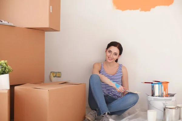 Woman choosing paint colour from swatch for new home sitting on wooden floor. Woman in the house — Stock Photo, Image