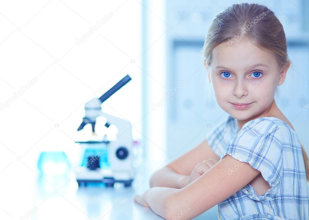 Schoolgirl looking through microscope in science class.