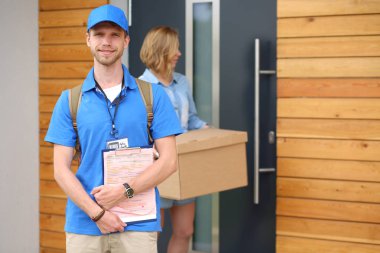 Mavi üniformalı gülümseyen kurye servis konseptine paket kutusu teslim eden teslimatçı. Mavi üniformalı gülümseyen teslimatçı.