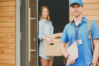 Mavi üniformalı gülümseyen kurye servis konseptine paket kutusu teslim eden teslimatçı. Mavi üniformalı gülümseyen teslimatçı.