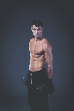 Yakışıklı kaslı adam dumbell ile çalışma dışarı. Kişisel fitness eğitmeni. Kişisel eğitim.