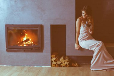 Seksi kadın şöminenin önünde. Ahşap şömine.