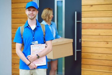 Mavi üniformalı gülümseyen kurye servis konseptine paket kutusu teslim eden teslimatçı. Mavi üniformalı gülümseyen teslimatçı.
