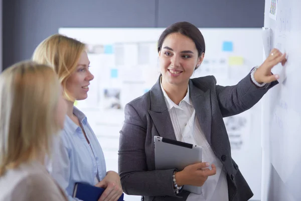 Business, education and office concept - business team with flip board in office discussing something — Stock Photo, Image