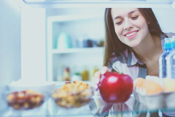 Retrato de fêmea em pé perto da geladeira aberta cheia de alimentos saudáveis, legumes e frutas. — Fotografia de Stock