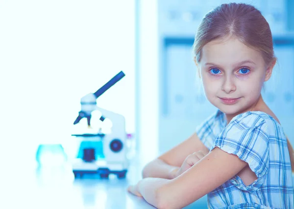 Mikroszkóppal a tudományos osztály keres iskoláslány. — Stock Fotó
