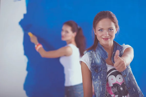 Дві молоді красиві жінки, що тримають кольорову палітру, стоять біля стіни. Дві молоді красиві жінки — стокове фото