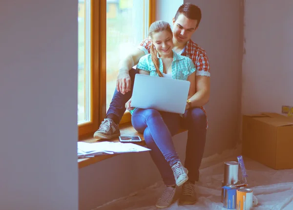 Retrato de jovem casal em movimento em nova casa sentado com laptop — Fotografia de Stock