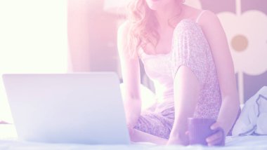 Evde dizüstü bilgisayar kullanan genç bir kadın.