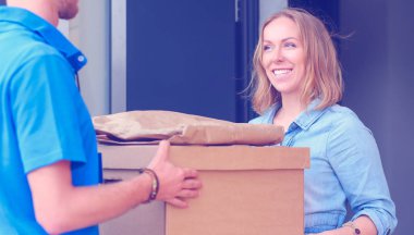 Mavi üniformalı gülümseyen kurye servis konseptine paket kutusu teslim eden teslimatçı. Mavi üniformalı gülümseyen teslimatçı.