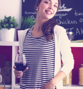 Güzel kadın mutfakta şarap içiyor.