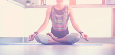 Genç kadın lotus pozisyonunda evde Yoga yapıyor. Yoga. Kadın. Yaşam tarzı
